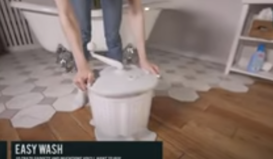 Person using manual washing machine to wash clothes.